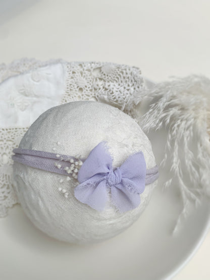 close up of the lilac bow headband on a foam ball to show size