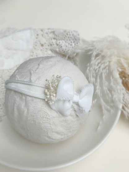 close up of the ivory bow headband on a foam ball to show size