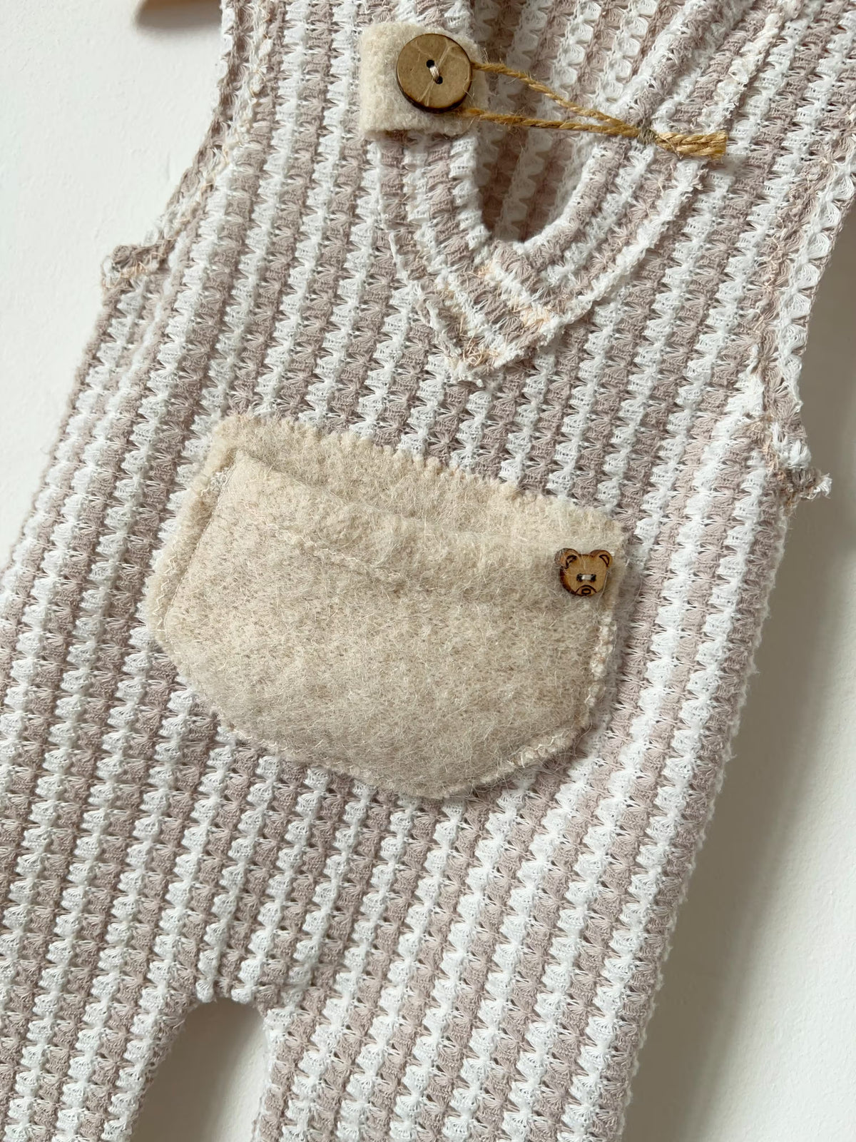 newborn boy romper for photo sessions in beige and cream with a cream pocket and small bear wooden button 