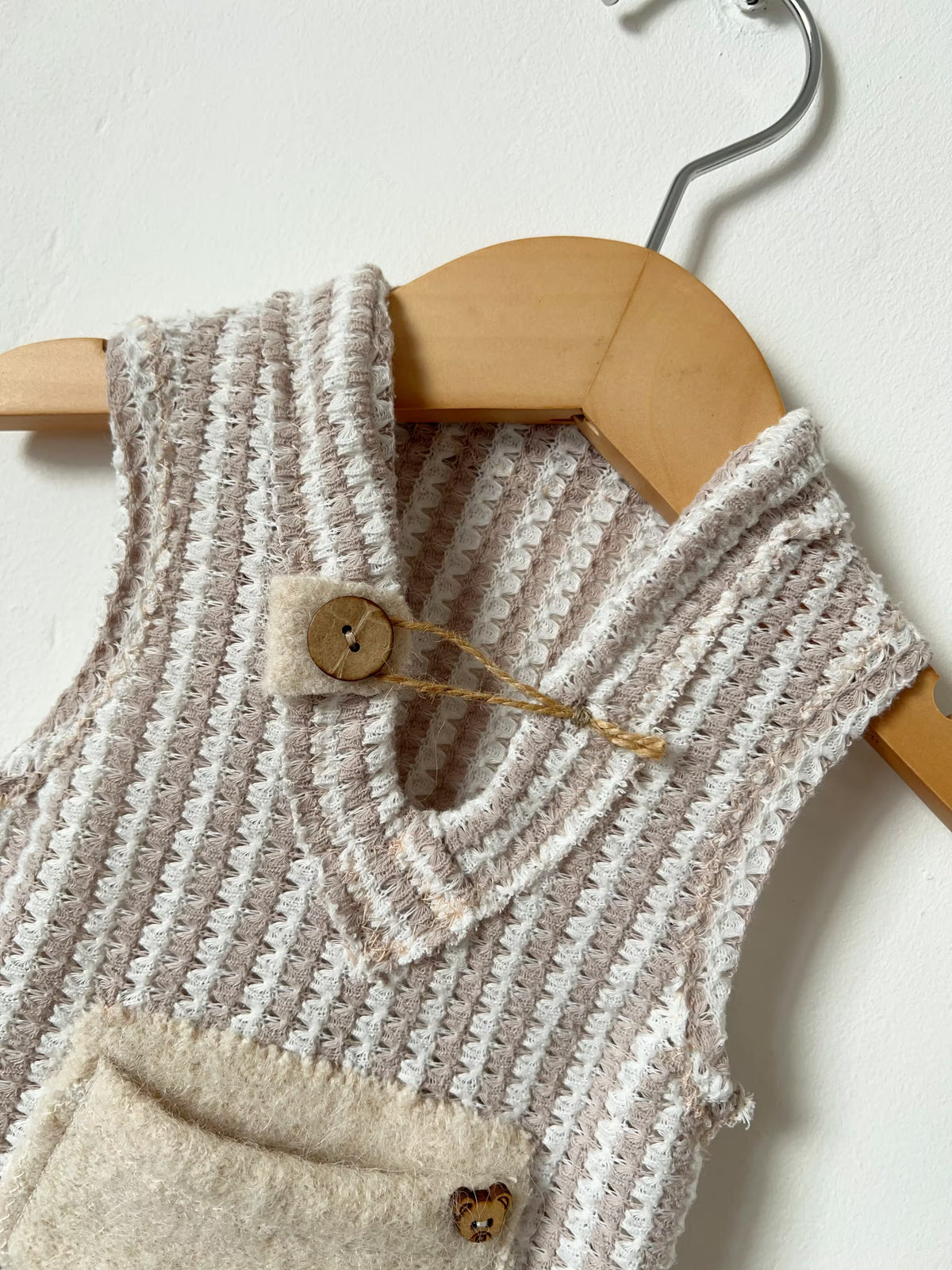 close up of the wooden details on the newborn beige romper 