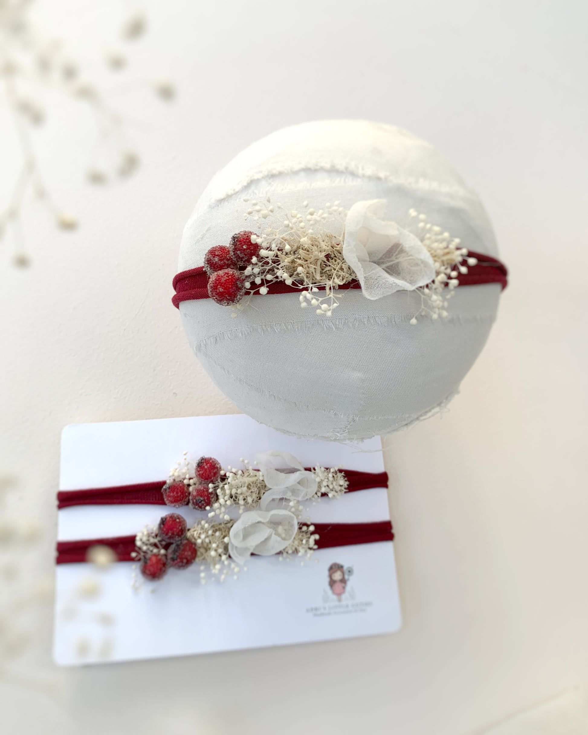 Baby headbands with red berries and white flowers on a white background