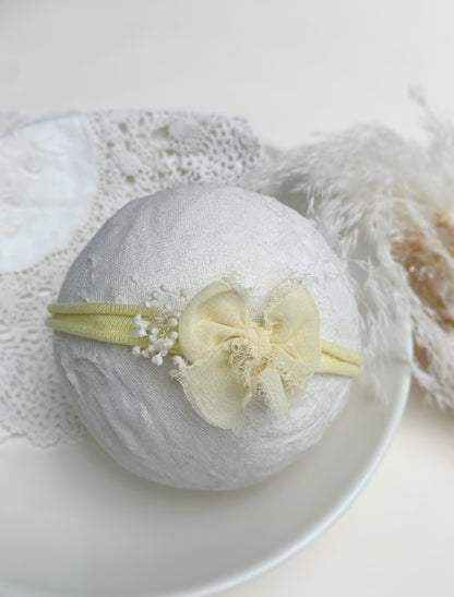 close up of the yellow bow headband on a foam ball to show size