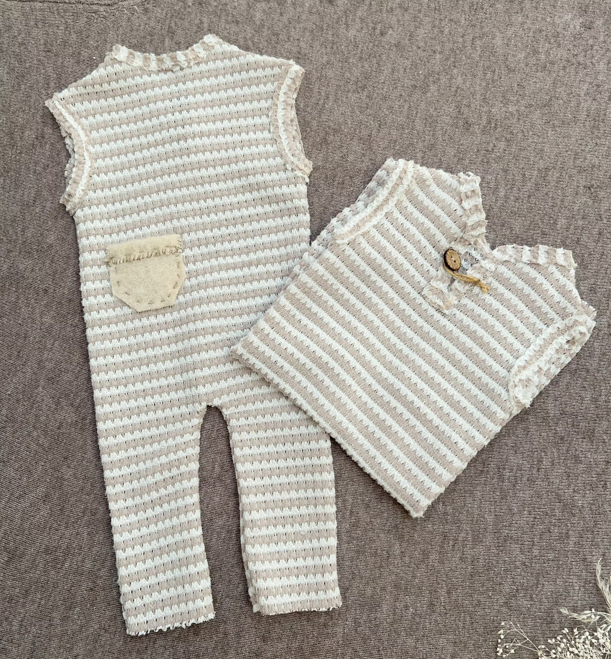 newborn baby boy rompers in beige and cream stripes on a brown backdrop