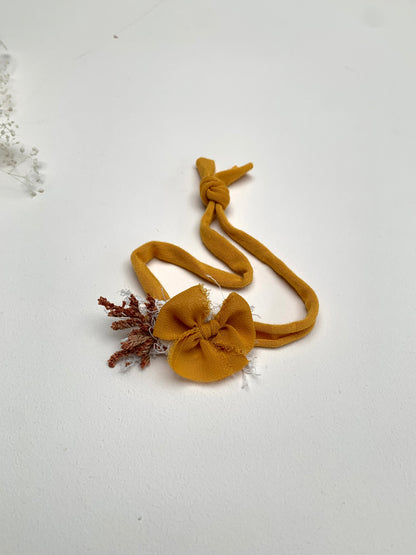 a mustard baby bow headband showing the knot to tie at the back, adjustable stretchy design 